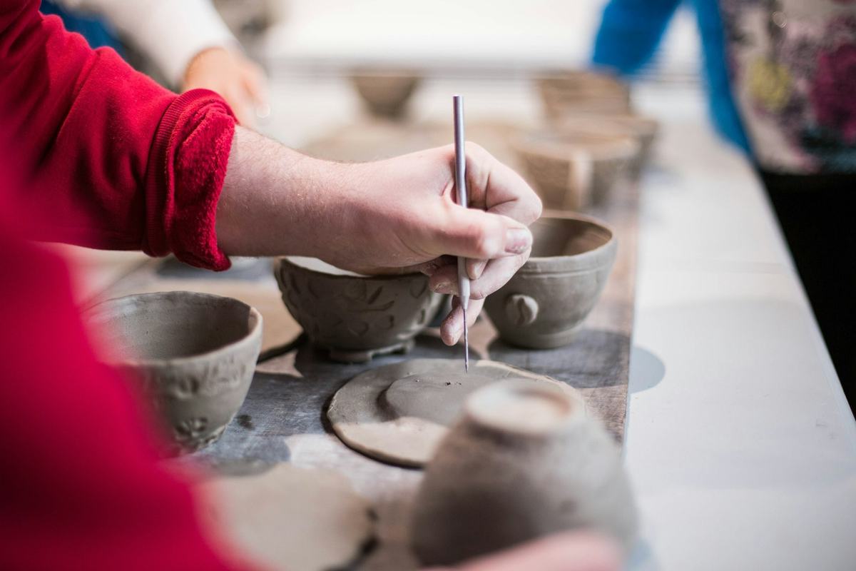 Hands painting a ceramic pot in a pottery studio